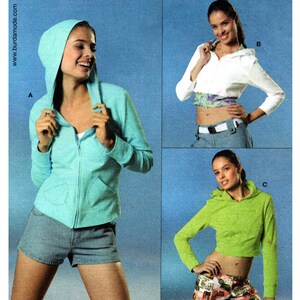 May include: Three women model different styles of hooded sweatshirts. The first model wears a light blue hooded sweatshirt with a zipper. The second model wears a white hooded sweatshirt with a cropped length. The third model wears a bright green hooded sweatshirt with a cropped length.