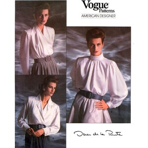 May include: Vogue Patterns American Designer, Oscar de la Renta, sewing pattern for a white blouse with a high collar and long sleeves. The model is wearing a black belt and a skirt.