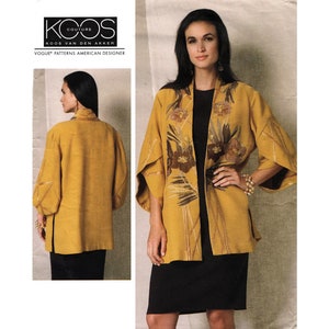 May include: A yellow jacket with a floral print and a black collar. The jacket has long sleeves and a loose fit. The model is wearing a black dress and has long brown hair.
