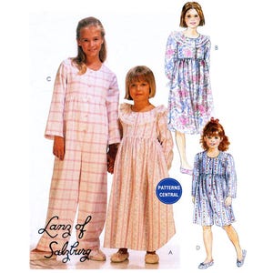May include: A sewing pattern for three girls' dresses. The pattern includes a long-sleeved, button-up dress with a plaid pattern, a long-sleeved, button-up dress with a floral pattern, and a short-sleeved, button-up dress with a floral pattern. The pattern is from Lanz of Salzburg.