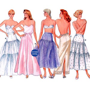 May include: Five different styles of white, pink, blue and cream layered tulle skirts. The skirts are shown on five different models. The skirts are all floor-length and have a variety of different embellishments.
