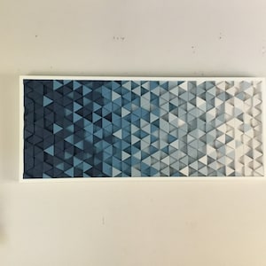 Peut inclure: Une &oelig;uvre d'art murale encadr&eacute;e pr&eacute;sentant un d&eacute;grad&eacute; de triangles bleus, passant du bleu fonc&eacute; au bleu clair et au blanc.