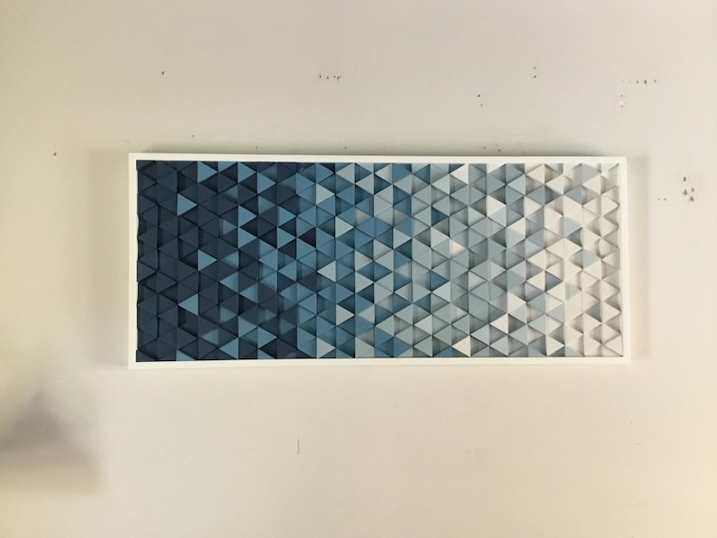Peut inclure: Une &oelig;uvre d'art murale encadr&eacute;e pr&eacute;sentant un d&eacute;grad&eacute; de triangles bleus, passant du bleu fonc&eacute; au bleu clair et au blanc.