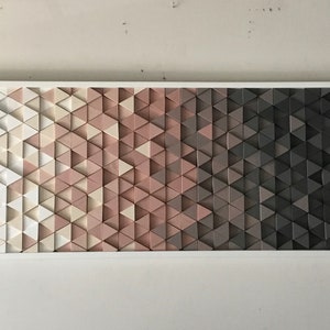 May include: A wall art piece made of a gradient of triangles in shades of white, pink, and gray. The triangles are arranged in a geometric pattern.