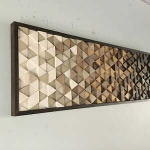 May include: A framed wall art piece with a geometric pattern of wooden triangles in shades of brown, beige, and white.
