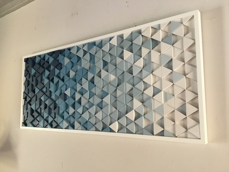 Peut inclure: Une &oelig;uvre d'art murale en bois compos&eacute;e de triangles de diff&eacute;rentes nuances de bleu et de blanc, dispos&eacute;s en d&eacute;grad&eacute;. Les triangles sont en 3D et cr&eacute;ent un effet textur&eacute;. L'&oelig;uvre est encadr&eacute;e d'un cadre blanc.