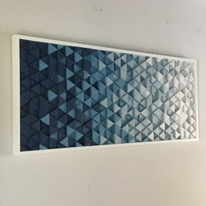 Peut inclure: Une &oelig;uvre d'art murale encadr&eacute;e pr&eacute;sentant un d&eacute;grad&eacute; de triangles bleus et blancs. Les triangles sont dispos&eacute;s selon un motif g&eacute;om&eacute;trique, cr&eacute;ant un design moderne et abstrait.