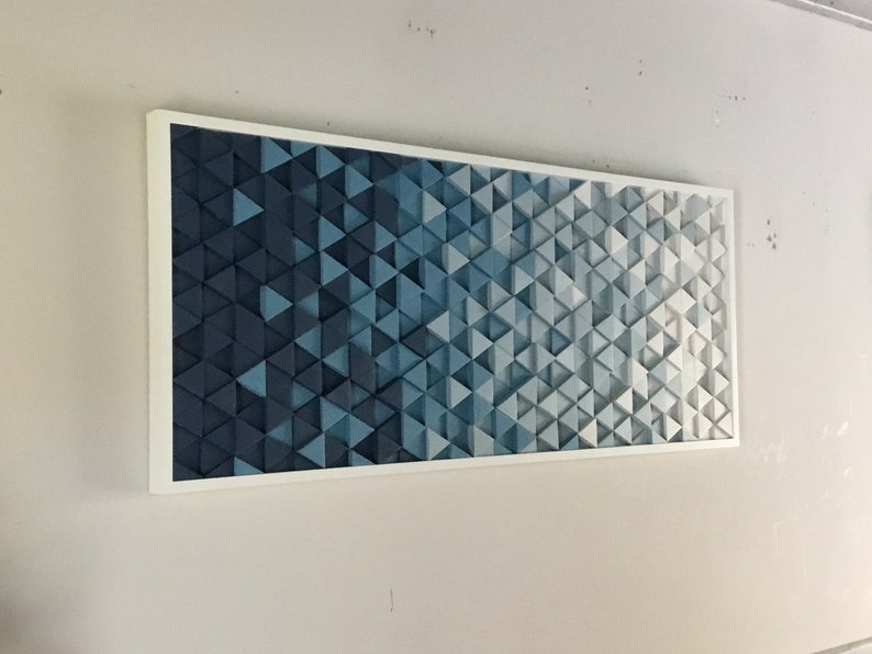 Peut inclure: Une &oelig;uvre d'art murale encadr&eacute;e pr&eacute;sentant un d&eacute;grad&eacute; de triangles bleus et blancs. Les triangles sont dispos&eacute;s selon un motif g&eacute;om&eacute;trique, cr&eacute;ant un design moderne et abstrait.