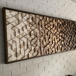 May include: A framed wall art piece made of wood with a geometric pattern of triangles in shades of brown and white.