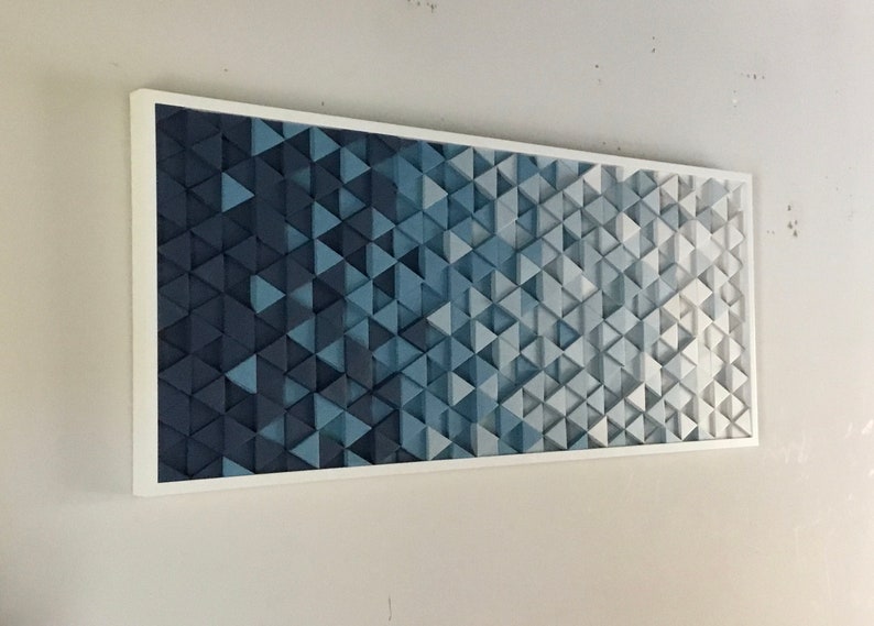 Peut inclure: Une &oelig;uvre d'art murale encadr&eacute;e pr&eacute;sentant un d&eacute;grad&eacute; de triangles bleus et blancs. Les triangles sont dispos&eacute;s selon un motif g&eacute;om&eacute;trique, cr&eacute;ant un design moderne et abstrait.