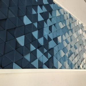 Peut inclure: Une &oelig;uvre d'art murale encadr&eacute;e pr&eacute;sentant un d&eacute;grad&eacute; de formes triangulaires bleues et blanches. Les triangles sont dispos&eacute;s en quinconce, cr&eacute;ant une impression de profondeur et de mouvement.