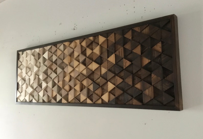May include: A wall art piece made of wood triangles in various shades of brown, from light to dark, arranged in a geometric pattern. The triangles are mounted on a black frame.