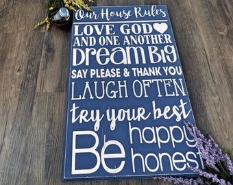 May include: Blue wooden sign with white text that reads "Our House Rules" followed by a list of rules: "Love God and one another", "Dream Big", "Say please & thank you", "Laugh often", "Try your best", "Be happy", "Be honest".