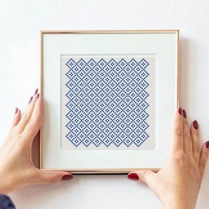 Könnte beinhalten: Ein gerahmter Druck mit einem geometrischen Muster aus blauen und weißen Quadraten. Der Druck ist in einem goldenen Rahmen und hängt an einer weißen Wand.