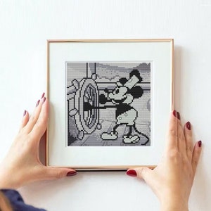 Könnte beinhalten: Ein gerahmter Schwarzweißdruck von Mickey Mouse in Matrosenkleidung, der ein Steuerrad hält.