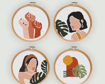 May include: Four embroidery hoop art pieces with a white background. The first hoop features three raised fists in different skin tones. The second hoop features a woman with black hair and a yellow top. The third hoop features a woman with brown hair and a white top. The fourth hoop features a geometric design with a yellow circle, a red rectangle, and a green leaf.