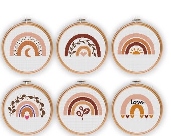 May include: Six embroidery hoops with different rainbow designs. Each hoop features a rainbow with various colors, including pink, orange, brown, and white. The designs include a crescent moon, a heart, a sun, leaves, and the word "love".