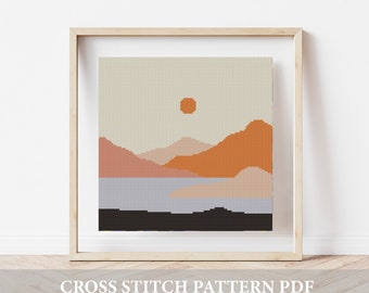 May include: A cross stitch pattern depicting a minimalist landscape with a sunset over mountains and a lake. The pattern is in a wooden frame and the text "CROSS STITCH PATTERN PDF" is below the frame.