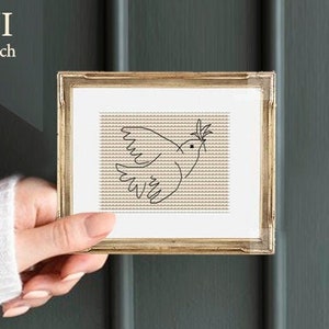 Może przedstawiać: Wzorzec haftu krzyżykowego w ramce przedstawiający gołębia z gałązką oliwną w dziobie. Wzór jest na beżowym tle, a gołąb jest obwiedziony czarną nicią. Ramka jest złota, a tło to ciemnozielona ściana.