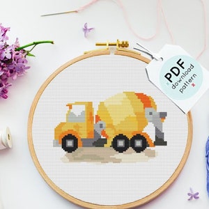 Puede incluir: Un patrón de punto de cruz de un camión mezclador de cemento amarillo sobre un fondo blanco. El patrón está en un aro de bordado de madera. La imagen también incluye cuatro madejas de hilo de bordar en tonos de azul, rosa y gris, y una etiqueta que dice "Patrón de descarga PDF".