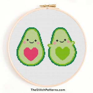 Peut inclure: Modèle de point de croix de deux moitiés d'avocat avec des visages et des cœurs. L'avocat à gauche a un cœur rose et l'avocat à droite a un cœur vert. Le motif est sur un fond blanc.