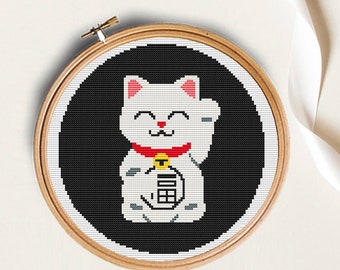 May include: White and gray lucky cat with a red collar and a gold bell, with a black background. The cat is holding up its right paw, a symbol of good luck.