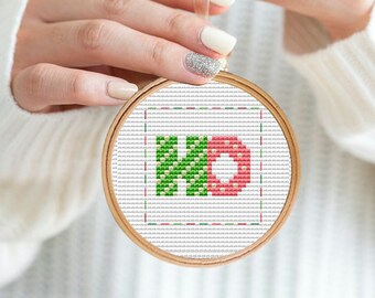 Op de afbeelding: Een witte borduurring met een groen en rood kruissteekontwerp van de letters "KD".