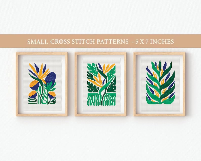 May include: Three framed cross stitch patterns featuring stylized floral designs in shades of green, blue, and yellow. Each pattern is 5 inches by 7 inches.