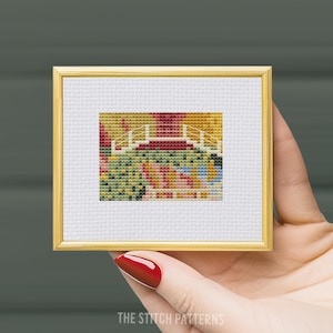 Puede incluir: Un patrón de punto de cruz enmarcado de un puente sobre un estanque con un paisaje colorido en el fondo.