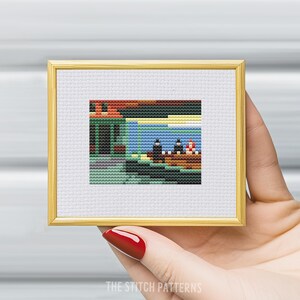 K&ouml;nnte beinhalten: Ein Kreuzstichmuster einer Malerei, die drei Figuren in einem Boot auf einem Gew&auml;sser zeigt. Die Figuren tragen schwarze Kleidung und das Boot ist rot. Der Hintergrund ist ein blauer Himmel mit einer gelben Sonne und einem gr&uuml;nen Geb&auml;ude.