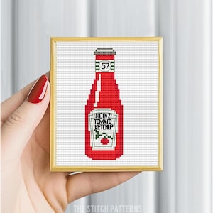 May include: A framed cross-stitch pattern of a red Heinz Tomato Ketchup bottle with the number 57 on the label.