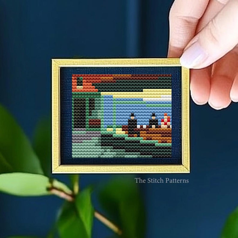 K&ouml;nnte beinhalten: Ein Kreuzstichmuster einer Malerei, die ein Haus mit rotem Dach und drei Figuren in einem Boot auf einem Gew&auml;sser zeigt. Das Muster ist in einem goldenen Rahmen gerahmt und der Text "The Stitch Patterns" befindet sich unter dem Rahmen.