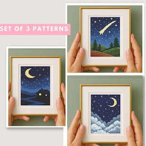 May include: A set of three framed cross-stitch patterns, each with a gold frame and white mount. The patterns depict night scenes: a crescent moon, a shooting star, and clouds with a crescent moon. The background is dark blue with white and yellow details.