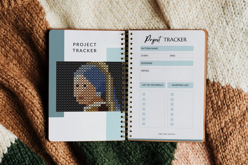 Pode incluir: Um caderno de rastreamento de projetos com uma capa azul e branca. O caderno tem uma encaderna&ccedil;&atilde;o em espiral e uma se&ccedil;&atilde;o para listar os materiais e uma lista de compras. A capa apresenta uma imagem pixelada de uma mulher com um len&ccedil;o azul.