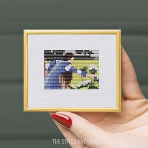 May include: Cross stitch pattern of a woman in a blue and white striped dress picking white flowers in a garden. The pattern is framed in a gold frame.