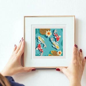 May include: A framed cross-stitch pattern featuring a blue pond with white and red koi fish swimming amongst lily pads and flowers.