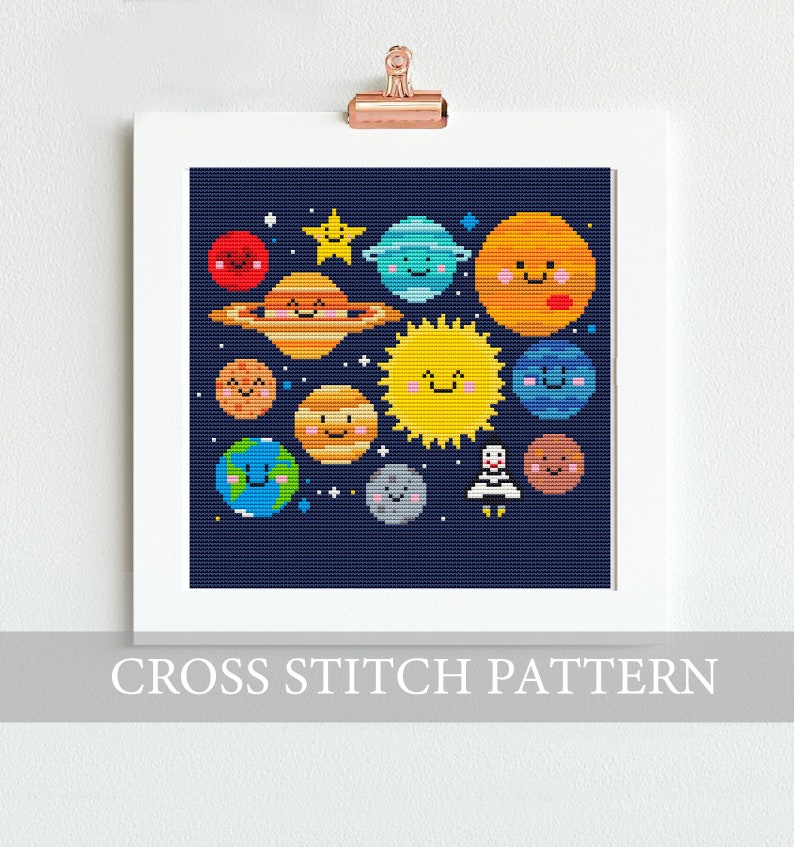 May include: A cross stitch pattern featuring a colorful depiction of the solar system with planets, stars, and a rocket. The planets have smiling faces and are arranged in a circular pattern against a dark blue background.