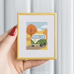 May include: A cross-stitch pattern of a green vintage van driving through an autumn landscape with orange and yellow leaves. The van has a white roof and white windows. The background is a blue sky with white clouds.