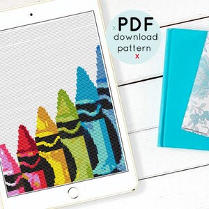 May include: A digital download pattern for a cross stitch design featuring a row of colorful crayons. The crayons are arranged in a diagonal line, with the red crayon at the bottom and the blue crayon at the top. The pattern is displayed on a tablet screen.