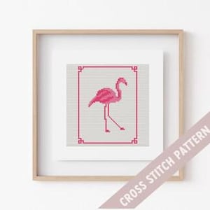 May include: Pink flamingo cross stitch pattern with a white background and a simple border. The pattern is framed in a light wood frame.