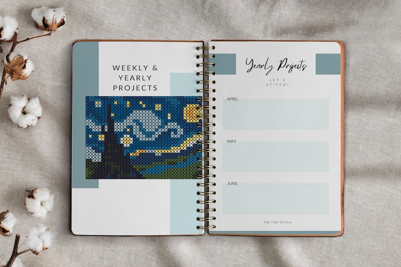 Pode incluir: Um caderno espiral com capa azul e branca. A p&aacute;gina da esquerda tem o texto "Weekly & Yearly Projects" e uma imagem de ponto cruz de uma noite estrelada. A p&aacute;gina da direita tem o texto "Yearly Projects Let's Stitch!" e uma lista de meses com espa&ccedil;os em branco para escrever.