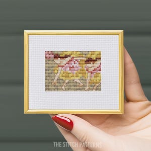 May include: Cross-stitch pattern of three girls in yellow and red dresses, framed in a gold frame.