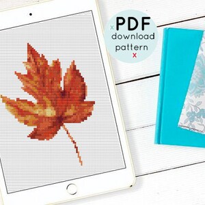 May include: A digital download pattern for cross-stitch featuring a single orange and yellow leaf. The pattern is displayed on a tablet computer.
