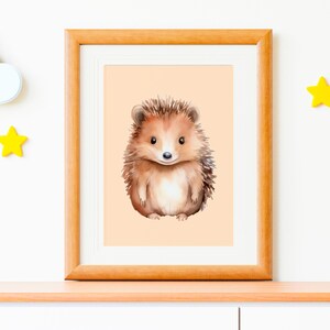 Pode incluir: Uma impressão em aquarela emoldurada de um ouriço. O ouriço é marrom com barriga branca, em um fundo cor de pêssego. A moldura é de madeira clara. Decorações de estrelas amarelas e nuvens brancas na parede.