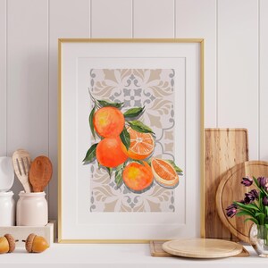 Pode incluir: Uma impressão em aquarela emoldurada com laranjas vibrantes e folhas verdes em um fundo padronizado. A obra de arte é exibida em uma moldura dourada, adicionando um toque de elegância à decoração da cozinha. Natureza morta.