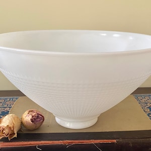 May include: A white milk glass bowl featuring a wide, smooth upper rim and a textured lower section with a repeating embossed grid pattern. The bowl has a circular base and a deep, conical shape, showcasing a clean, opaque finish throughout.