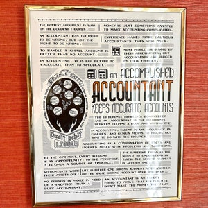 May include: A framed black and white poster with a humorous quote about accounting. The poster features a balance sheet with a hand holding a credit and debit ledger. The text reads "The hottest argument is won by the coldest figures." and "An accomplished accountant keeps accurate accounts."