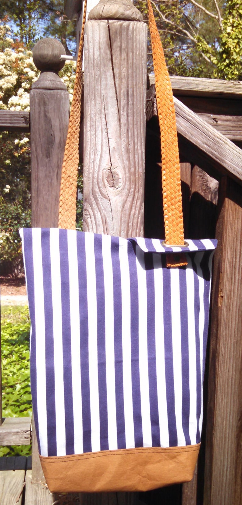 So sharp in navy and white stripes This totepurse has one leather strap that is unique and holds the flaps closed when purse is held.