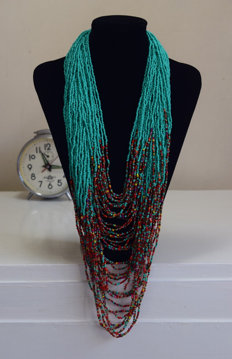 Puede incluir: Un collar largo de cuentas turquesa y multicolores. El collar est&aacute; hecho de cuentas peque&ntilde;as y est&aacute; en capas para crear un efecto en cascada.