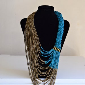 May include: A long, layered necklace with a braided section. The necklace is made of gold and turquoise beads.